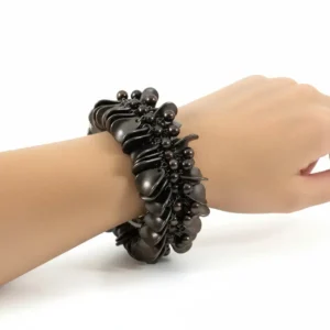 Beyaz fon üzerinde manken bileğinde yaprak motifli antik metal chunky bileklik detay çekimi.